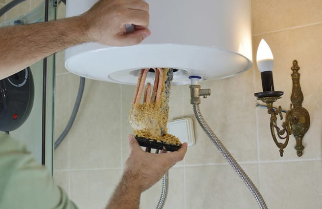 Technician removing mineral buildup from a water heater in Colorado Springs