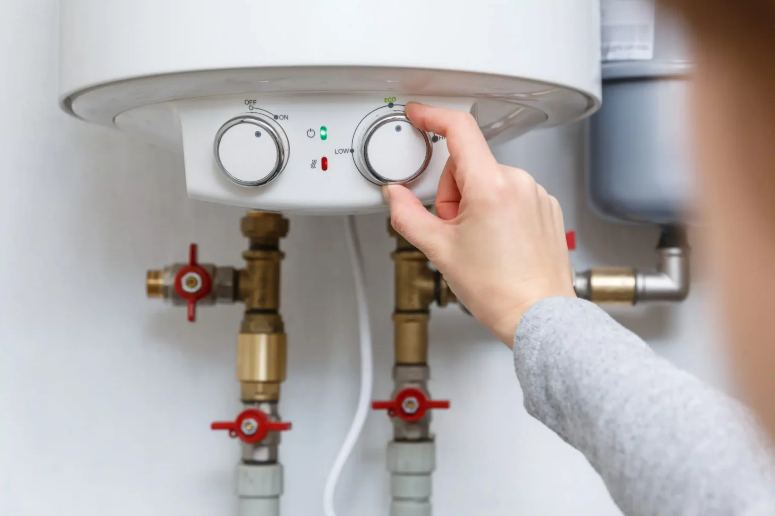 Homeowner adjusting the temperature controls on a water heater in Colorado Springs
